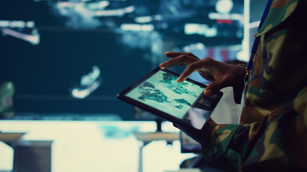 Business professional analyzing global logistics data on a digital tablet, with real-time shipping routes and supply chain visuals on a large display screen in the background.
